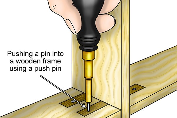 Pushing a in a pin on a wooden frame using a push pin
