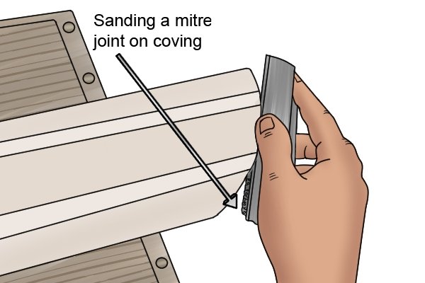 Sanding a mitre joint cut on coving to improve its finish and accuracy