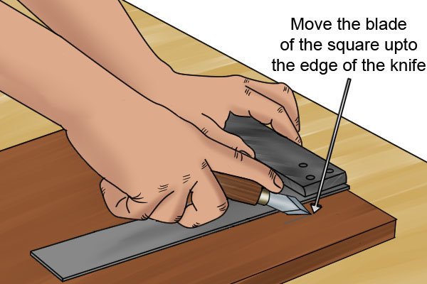Move the blade of the square up to the edge of the knife.
