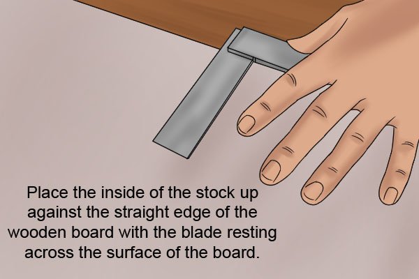 Place the inside of the stock up against the straight edge of the wooden board with the blade resting across the surface of the board.