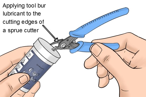 Applying tool bur lubricant to the cutting edges of a sprue cutter to keep them sharp fro longer.