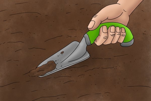 Placing the garden trowel blade into the soil