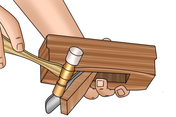 Adjusting a wooden p;lane's blade with a hammer