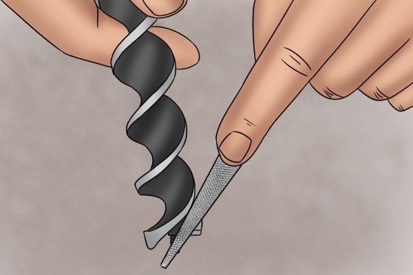 Image of a DIYer sharpening the cutting edge of an auger bit with a file