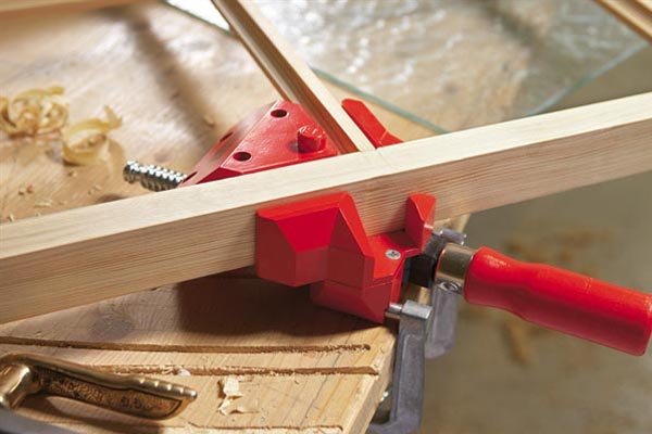 AN angle clamp holding two pieces of wood in the shape of a T