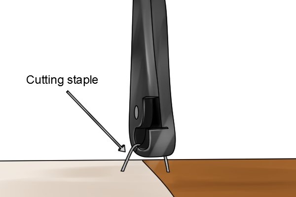 Cutting through staple on underside of wooden chair