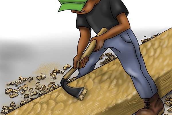 Image of a DIYer who is in the process of smoothing out the surface of a piece of wood using a foot adze