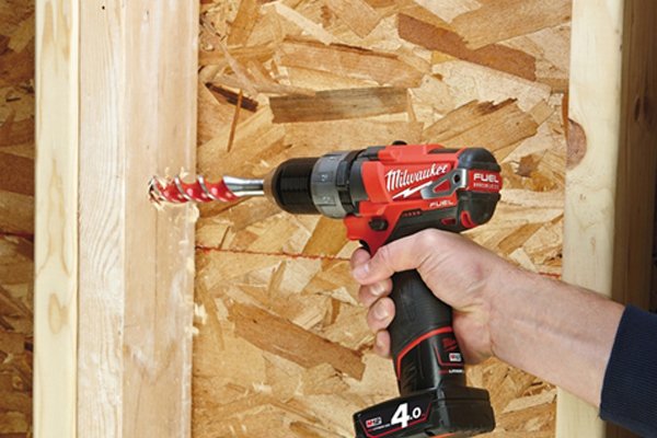 Orange cordless drill driver drilling a hole in a piece of wood