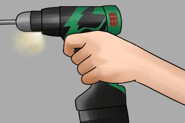 Hand holding the speed control trigger on a cordless drill driver activating the LED light
