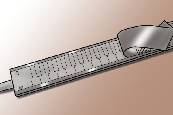 Underneath the scale of the caliper, there are a number of rectangular plates engraved onto a copper or glass strip. 