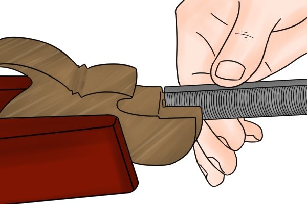 Image of a DIYer taking advantage of a vixen file's clog resistant teeth to shape a wooden saw handle