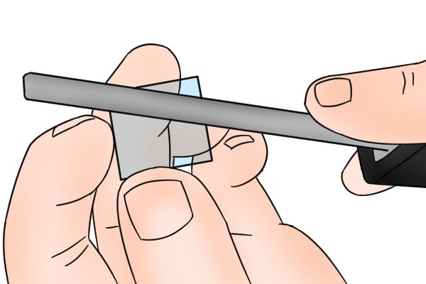 A DIYer using a diamond file to shape a piece of glass