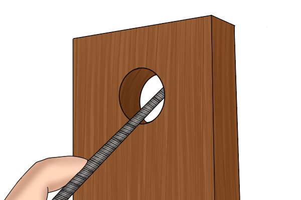 Image of a DIYer filing a hole in a door with a round file