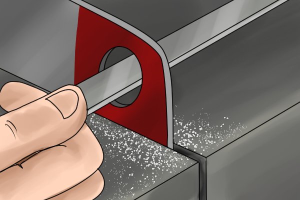 A DIYer using a machinist's file to smooth down the edges inside a slot