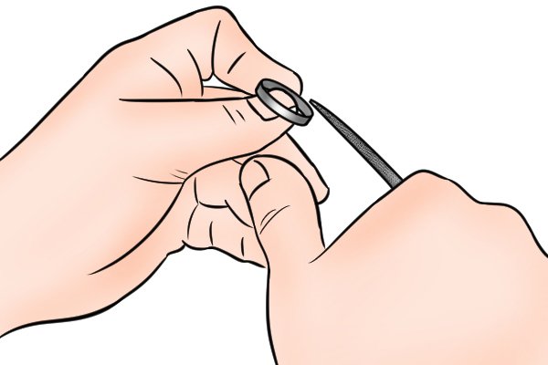 Image of a DIYer using a ring file to file the inside of a ring