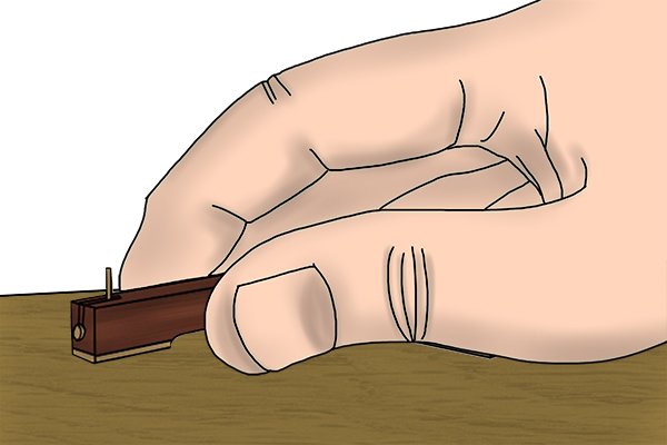Using a cutting gauge to mark out a precision line on a small piece of wood, contrast to panel gauge used to mark large wooden boards