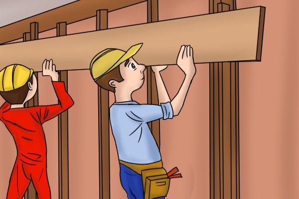 two people lifting up a load bearing lintel beam