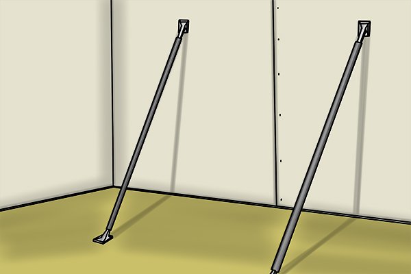 Adjustable support props holding up a drywall sheet on a wall
