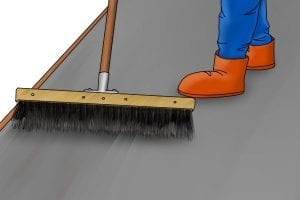 Using a broom to create a lined finish to floated concrete after installation.