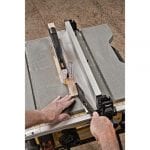 DEWALT DWE7490X 10-Inch Job Site Table Saw in use cutting wood with a push stick