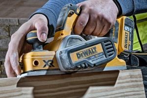 Individual using a DeWalt planer on wooden block.