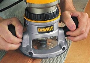 Using Dewalt hand router on a wooden material.